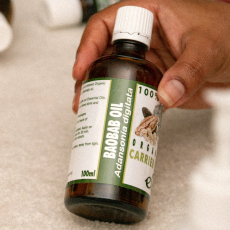Bottle of Baobab oil held by a hand on a neutral background