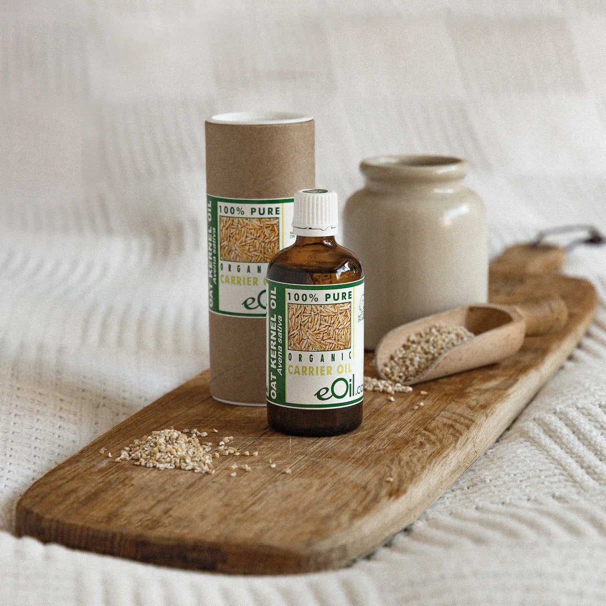 eOil carrier oil bottle and cardboard tube on a wooden board with seeds.